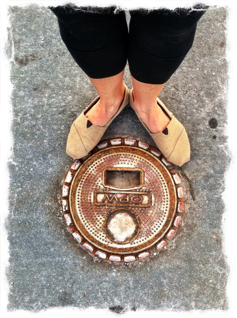 Feet standing on an ornate metal manhole cover