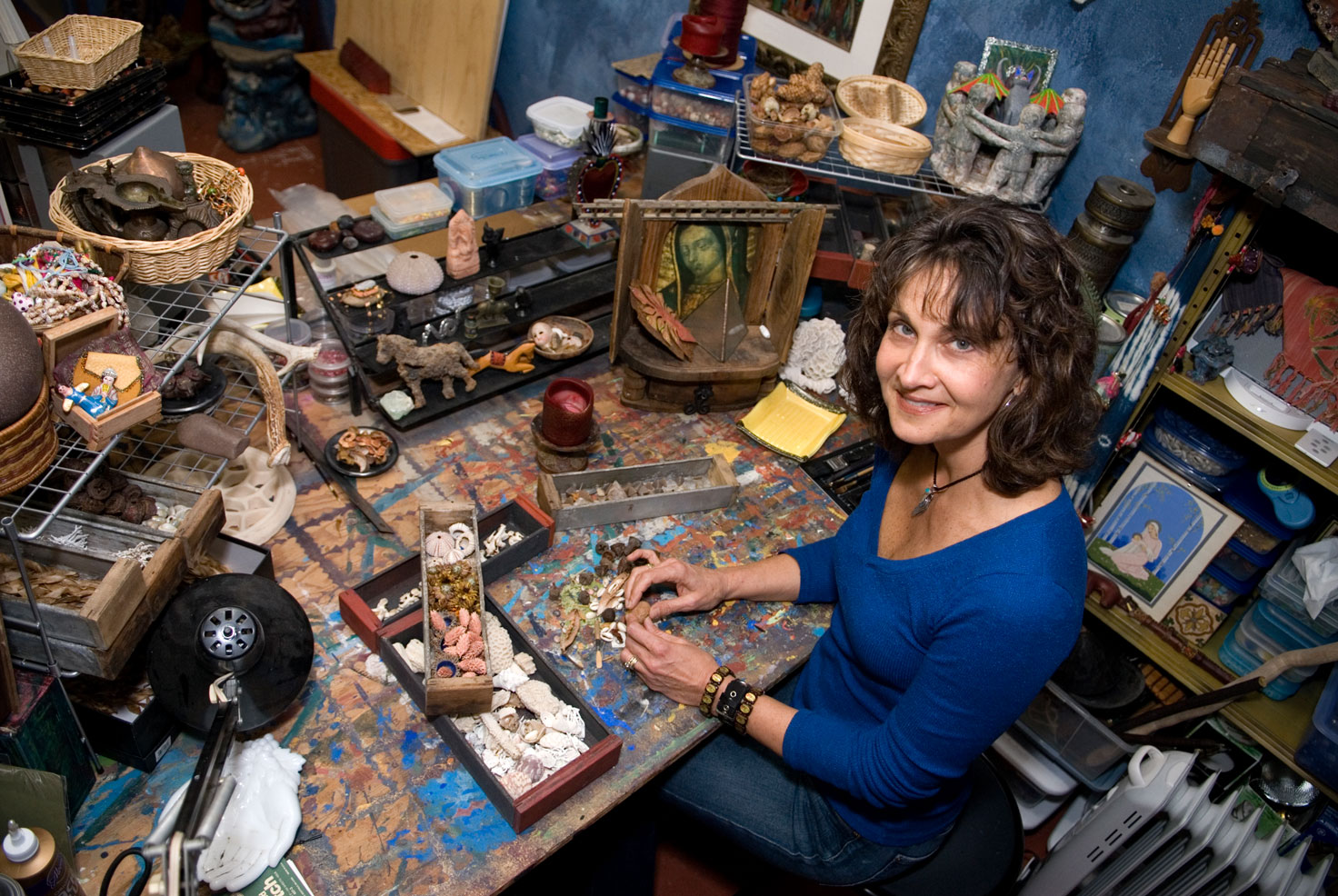 Heidi Darr-Hope at a cluttered art desk with supplies and works-in-progress