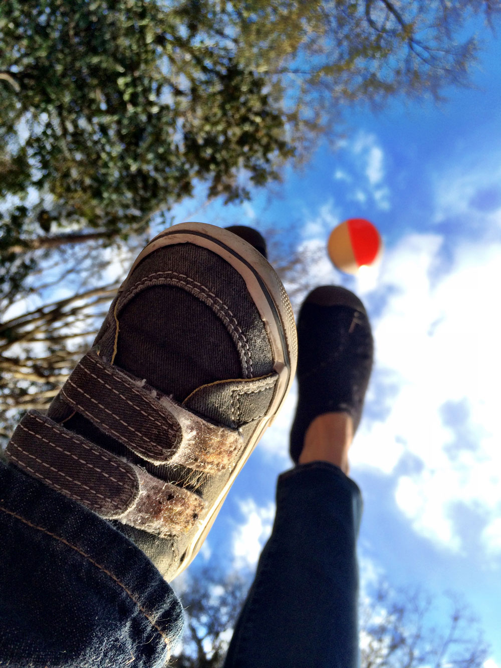 Foot in sneaker with orange ball against blue sky